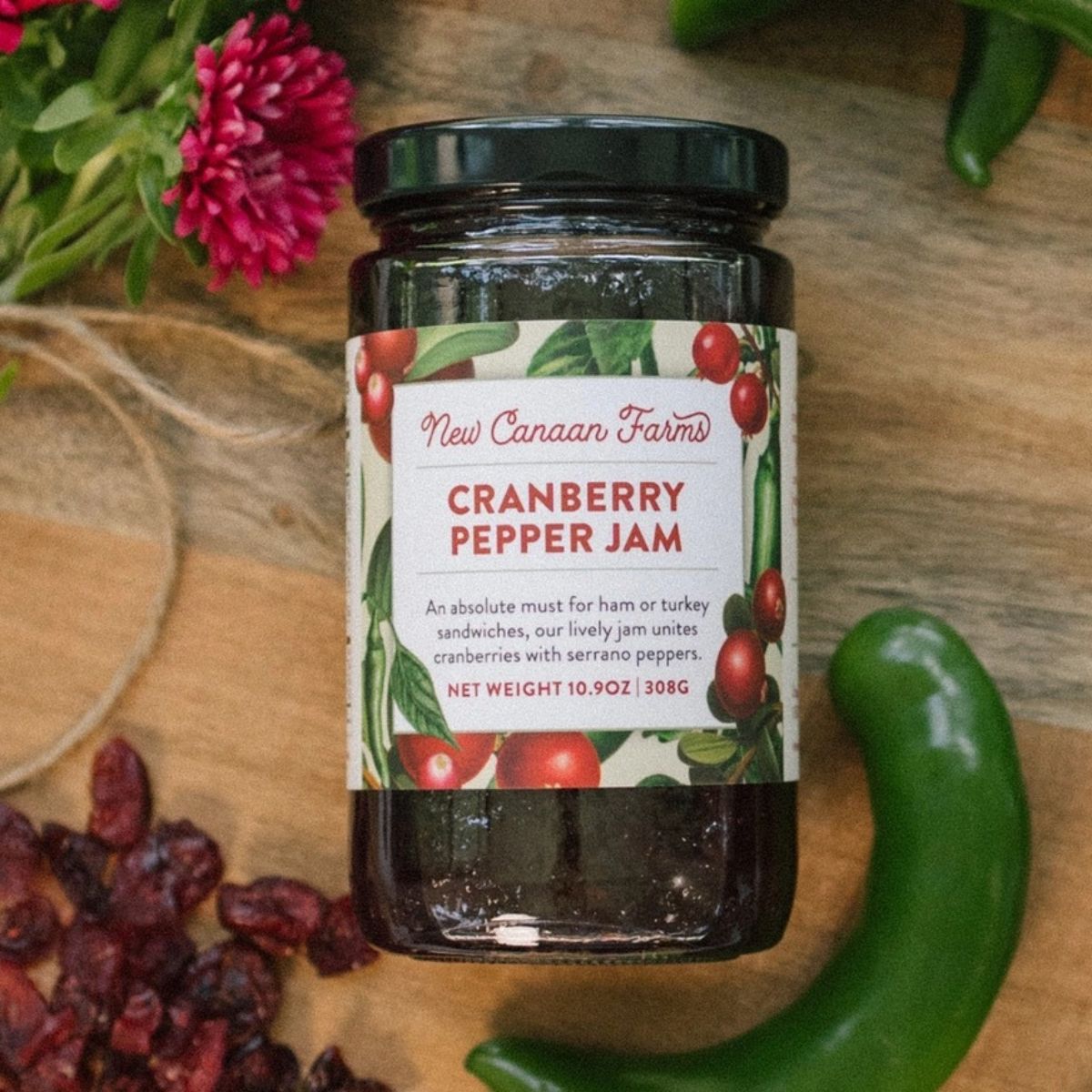 a jar of cranberry pepper jam laying flat on a table surface