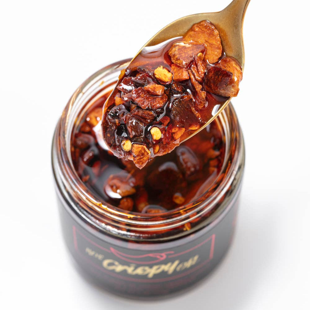Jar of hot pepper jelly with a spoonful on a white background