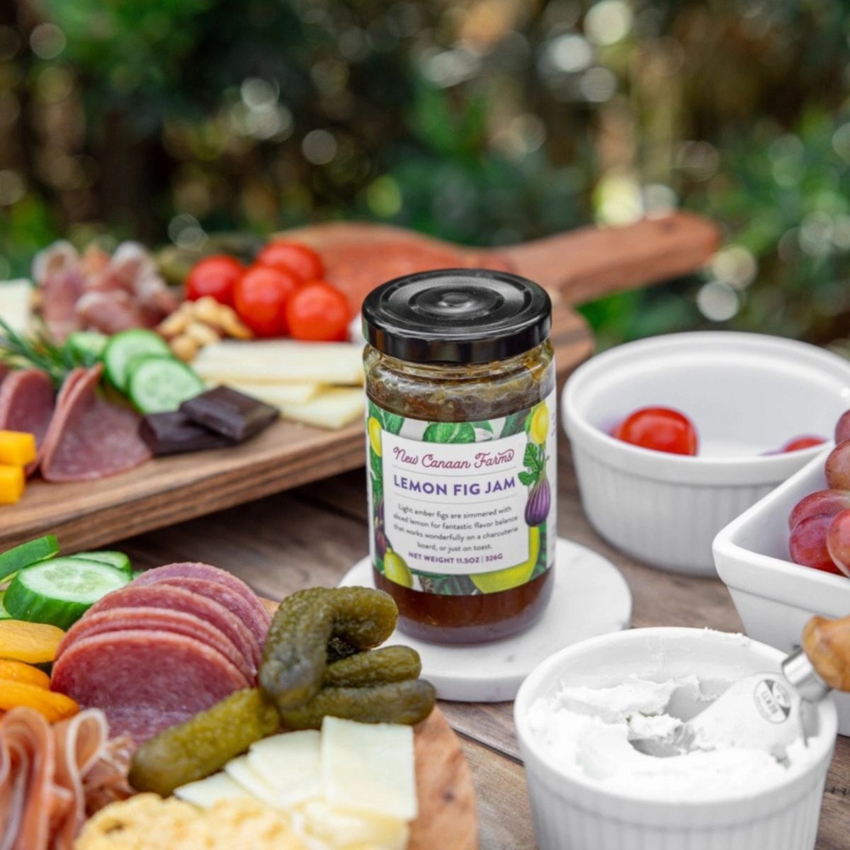 a jar of lemon and fig jam surrounded by a cheese board