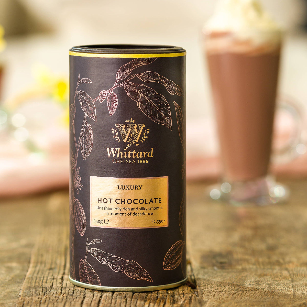 Whittard hot chocolate canister on a wooden surface with a blurred background