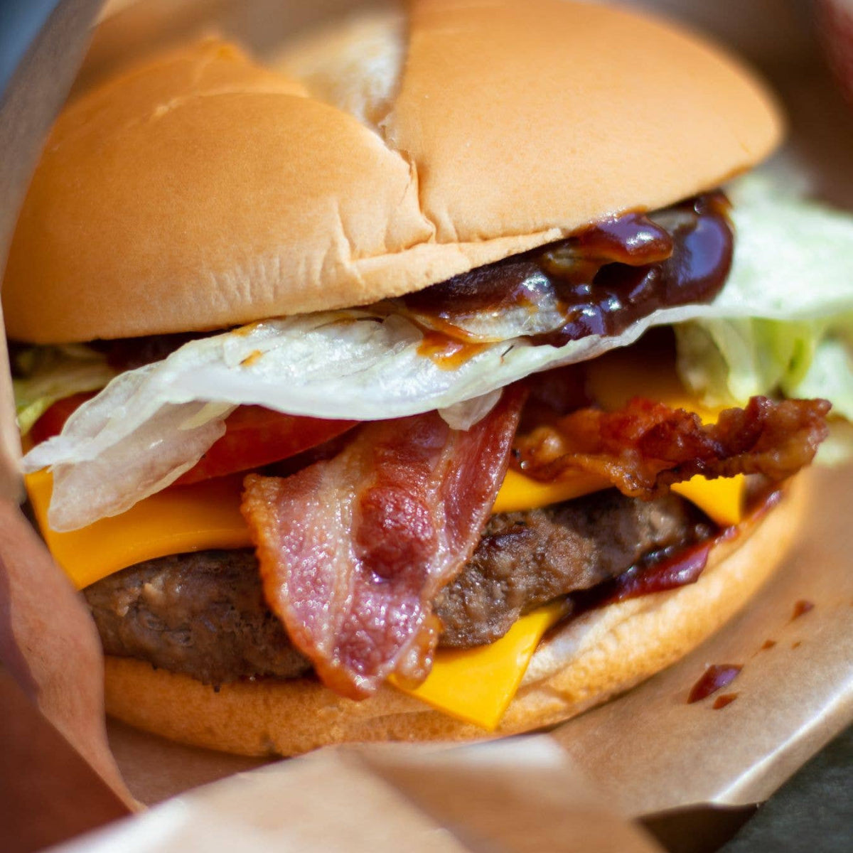 Deluxe burger with bacon, cheese, and egg on a bun, Tait Farm Savory Burger Toppings text overlay.