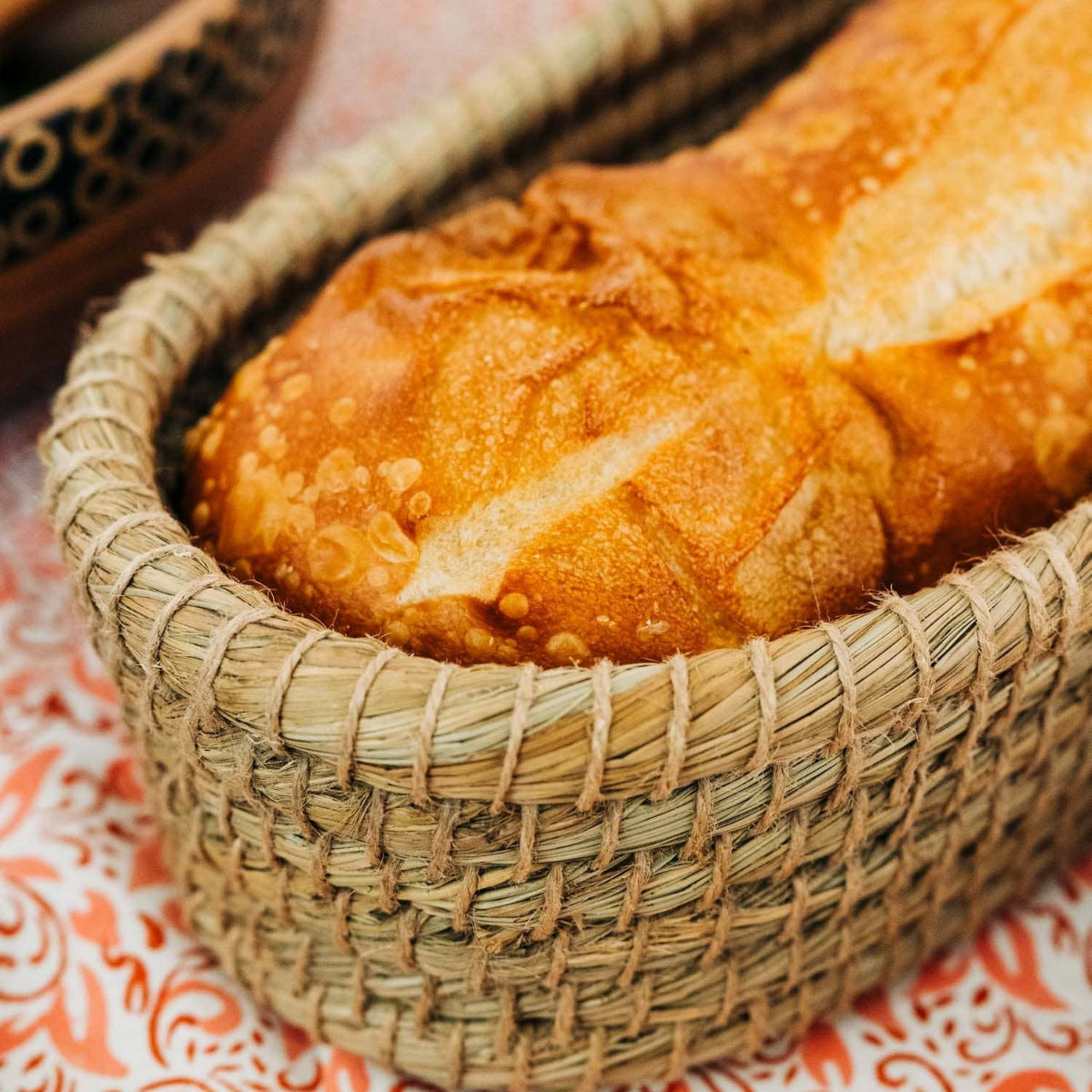 Loaf of bread in a woven basket on a patterned surface