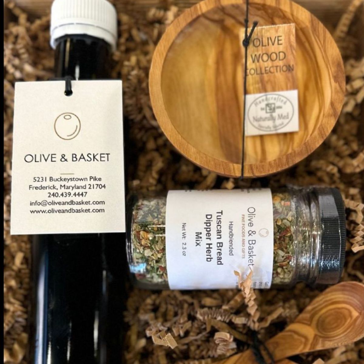 Olive oil bottle, herb container, and wooden bowl with 'Olive & Basket' branding on a textured background.