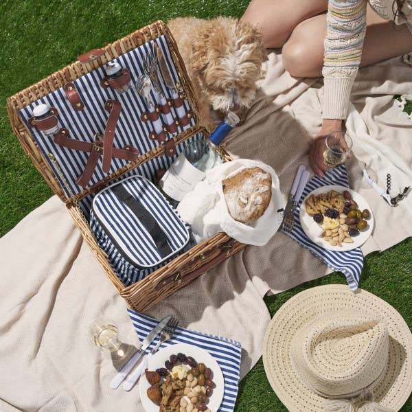 overhead shot of Picnic outside with a food basket filled with olives, breads, dipping oils 