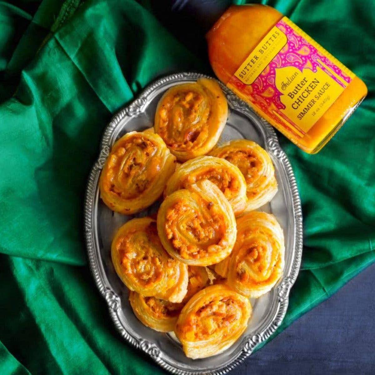 Silver tray with round baked items on a green fabric background