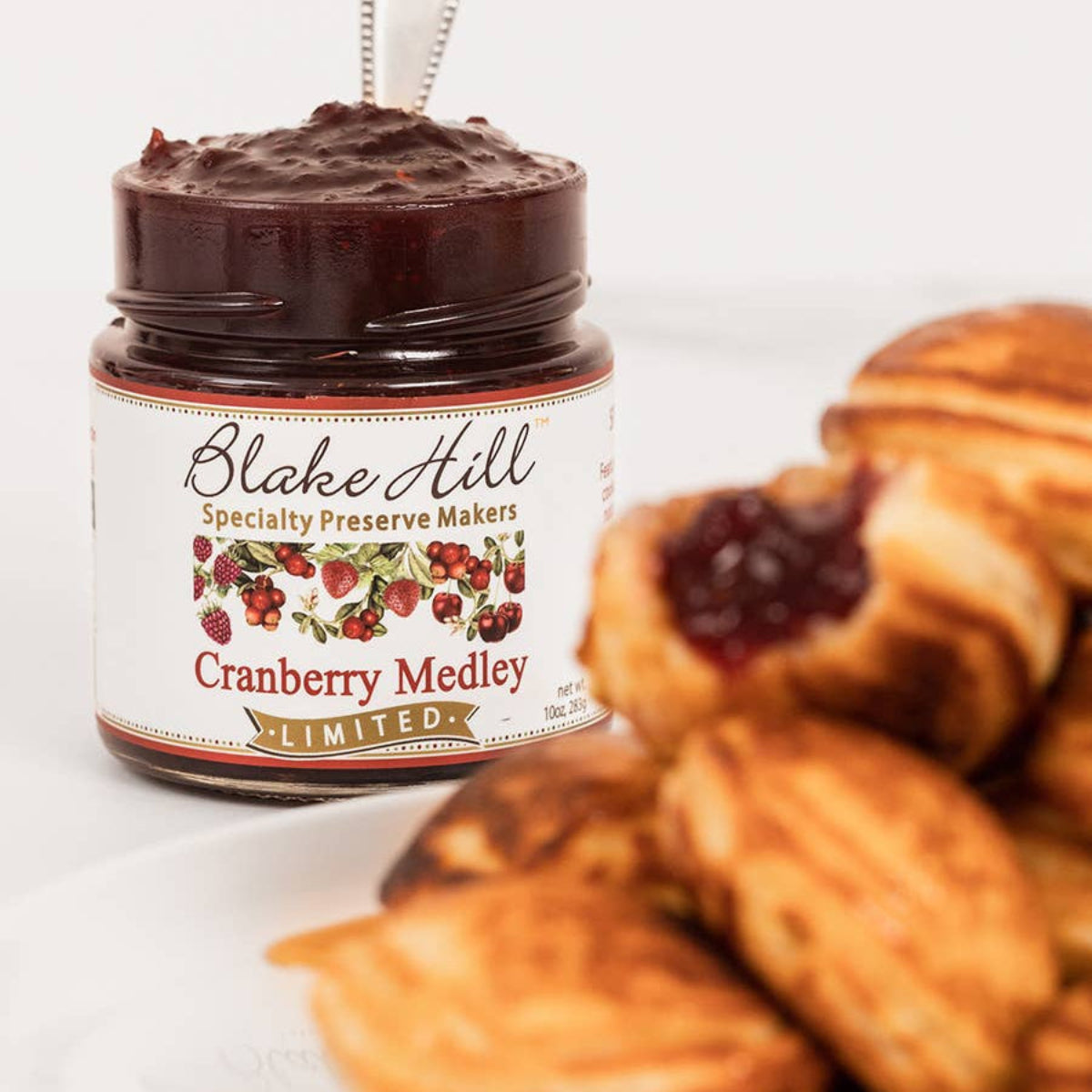 Jar of cranberry medley spread on a plate with pastries