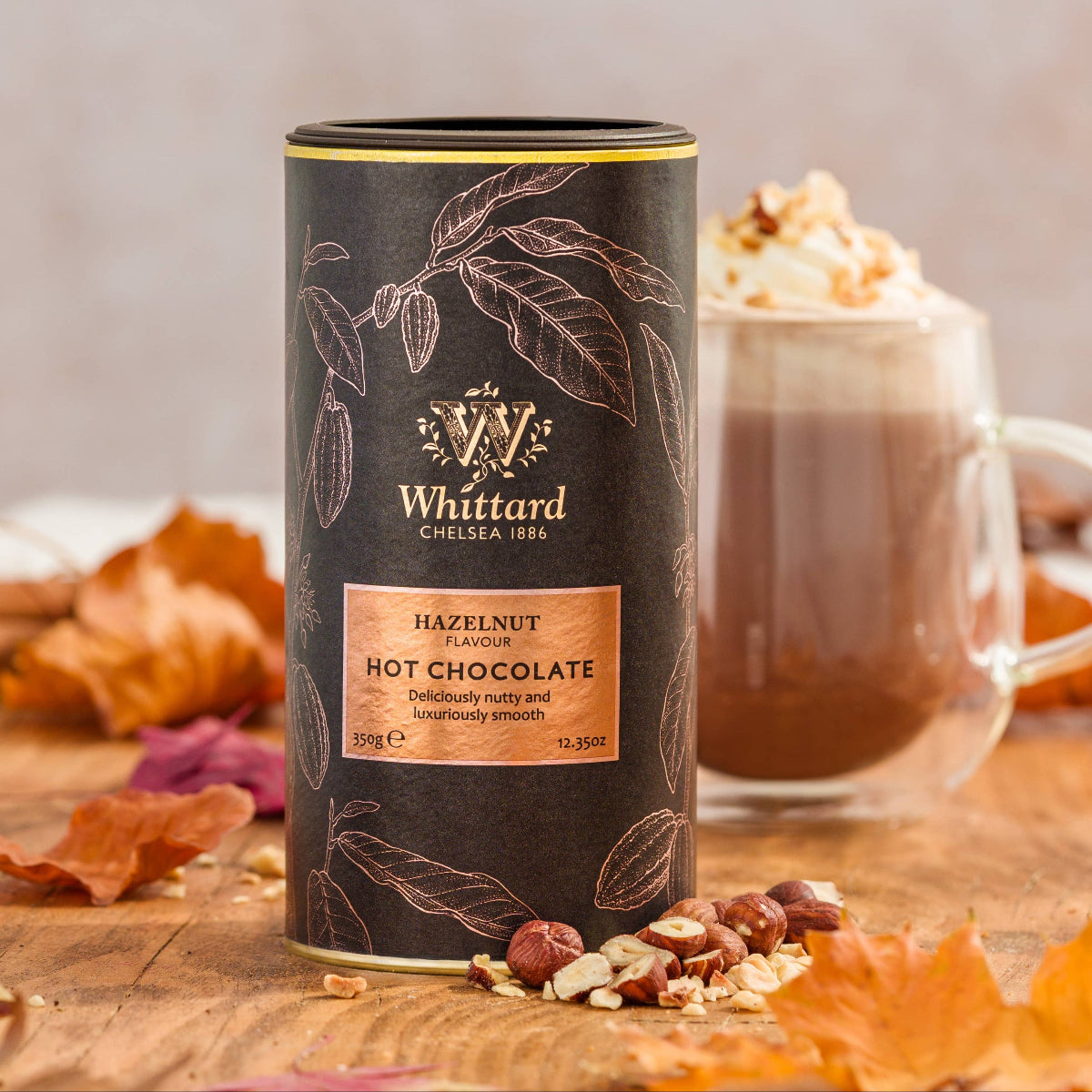 Whittard hazelnut hot chocolate canister on a wooden surface with a blurred background