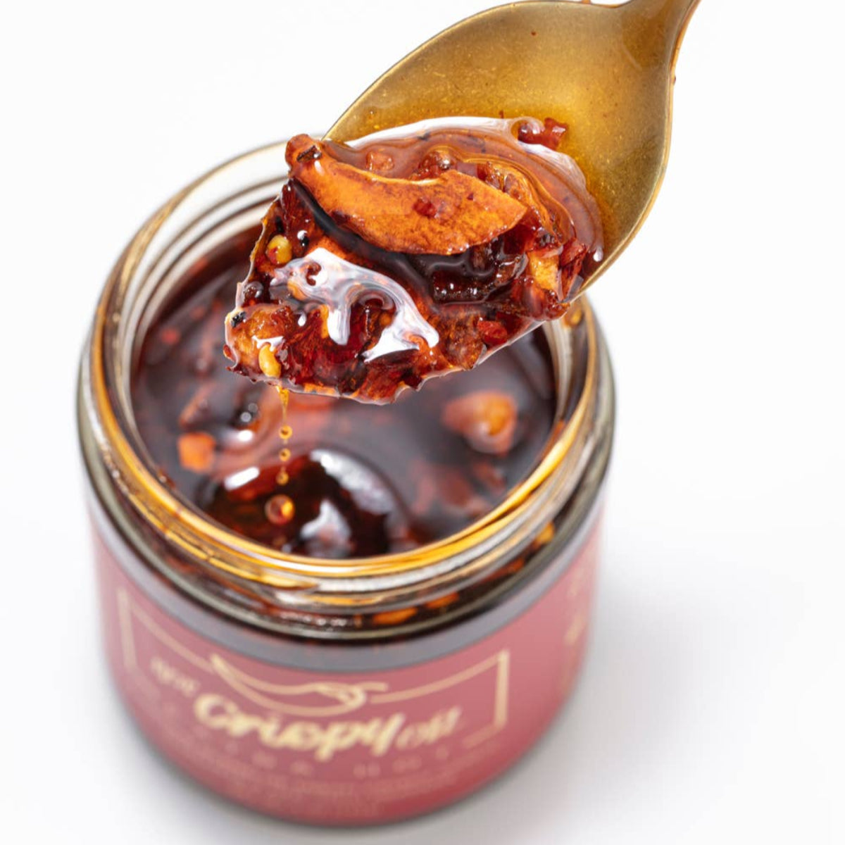 Jar of chutney with a spoonful being lifted, on a white background