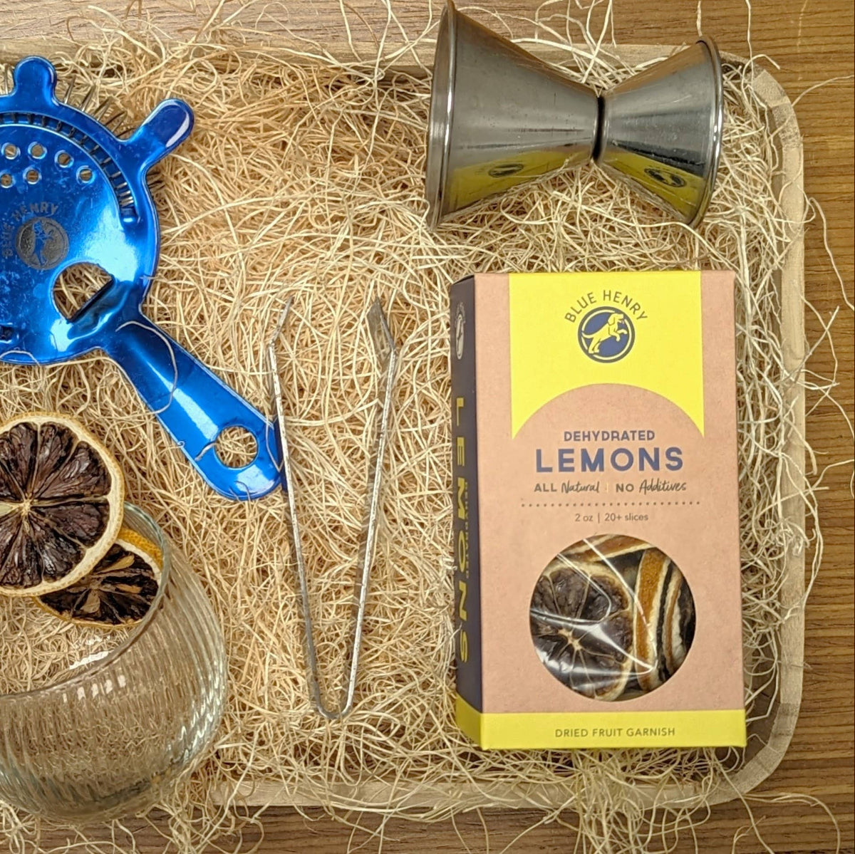 Bartending tools and Blue Heart lemon packaging on a wooden surface