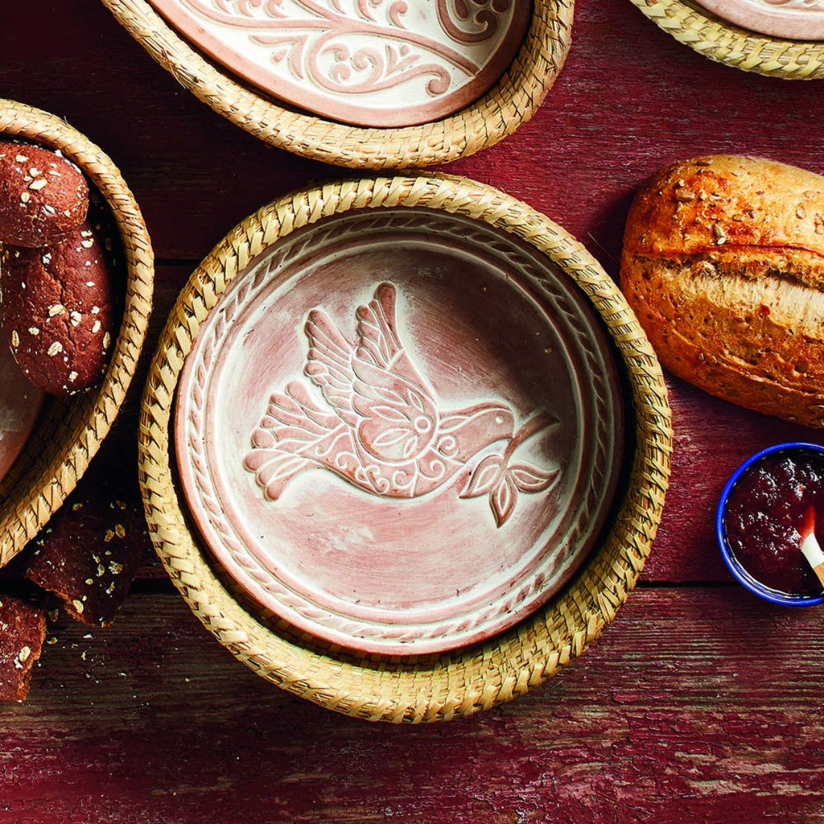 Decorative ceramic plate with bird design on a wooden surface with bread and jam.