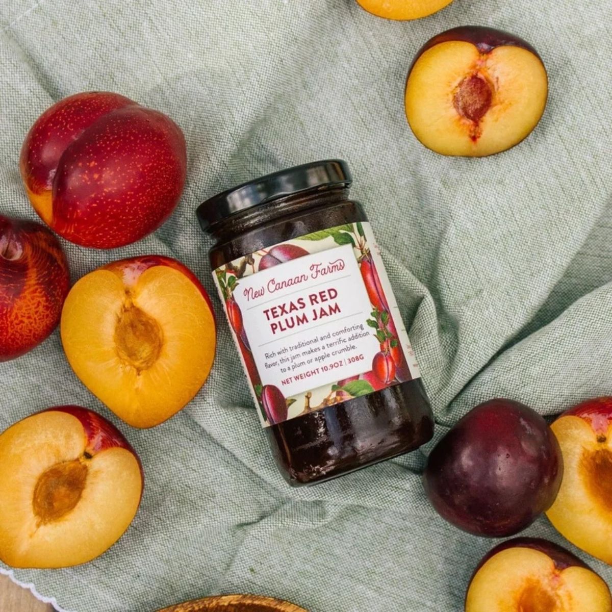 jar of plum jam laying flat surrounded by fruit