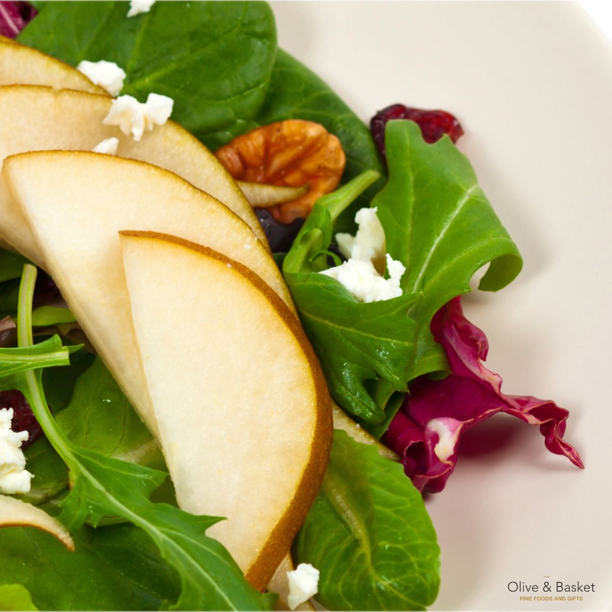 Salad with pears, goat cheese, and nuts on a white plate
