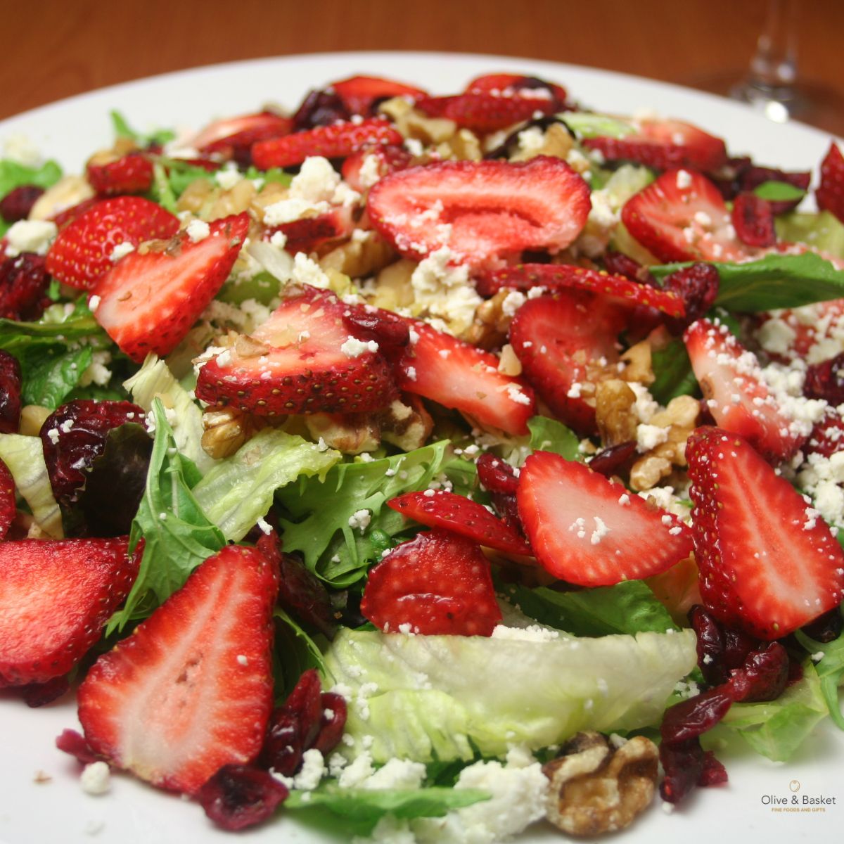 Salad with strawberries, nuts, and cheese on a white plate